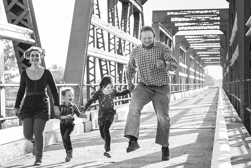 Happy family running together on a bridge