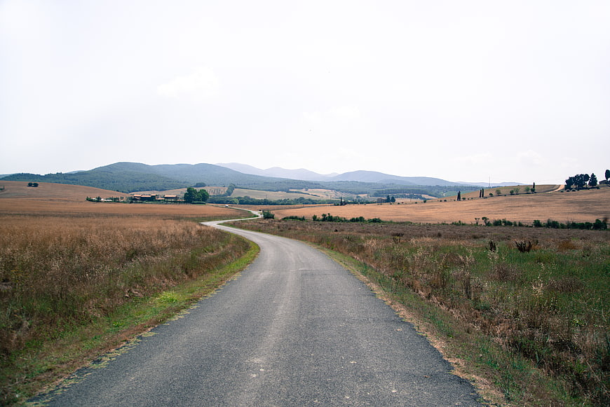 Winding asphalt road through dry Tuscan hills