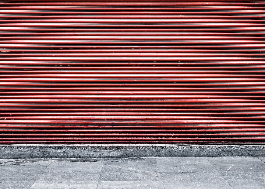 Red metal shutter door on urban street background
