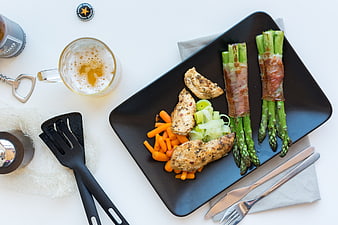Top view of grilled chicken, asparagus, and carrots with beer
