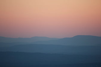 Layered Blue Mountain Silhouettes Under Pink Sunset Sky
