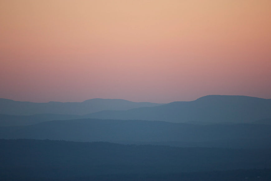 Layered Blue Mountain Silhouettes Under Pink Sunset Sky