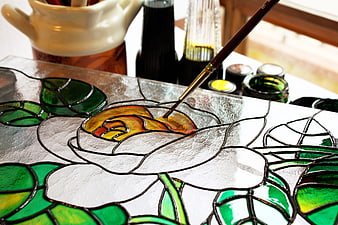 Close-up of hand painting a stained glass flower design