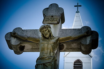 Stone Crucifix Statue with Church Steeple Background