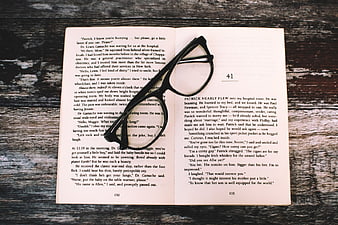 Open Book with Black Glasses on Rustic Wood