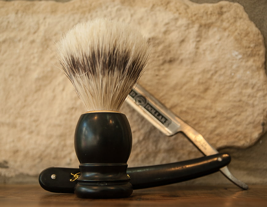 Classic shaving brush and straight razor on wooden surface