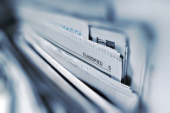 Close-up of Classified Newspaper Stack with Blue Tint