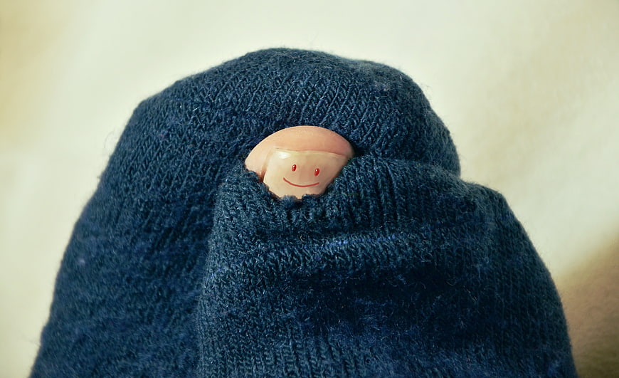 Funny toe peeking through hole in blue knitted sock