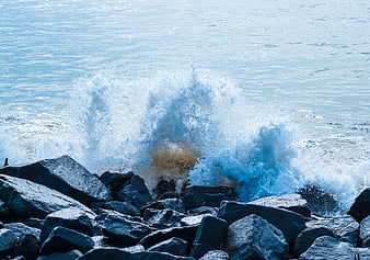 Powerful Ocean Wave Crashing Against Dark Rocks