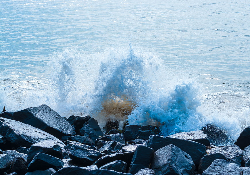 Powerful Ocean Wave Crashing Against Dark Rocks