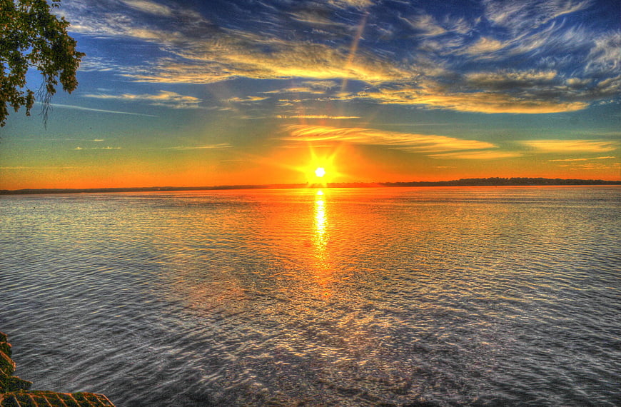 Vibrant Sunrise Over Calm Lake With Golden Reflections