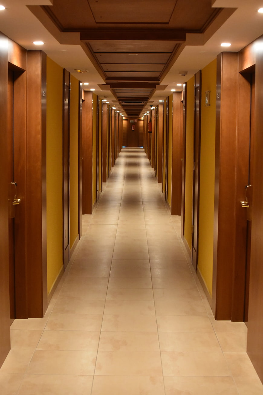 Symmetrical Hotel Hallway with Wooden Doors and Yellow Walls