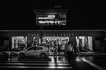 Black and white night street scene with taxi and pedestrians