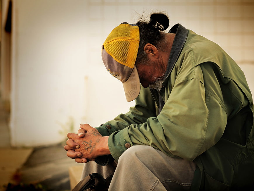 Homeless Man Sitting with Head Down in Prayer