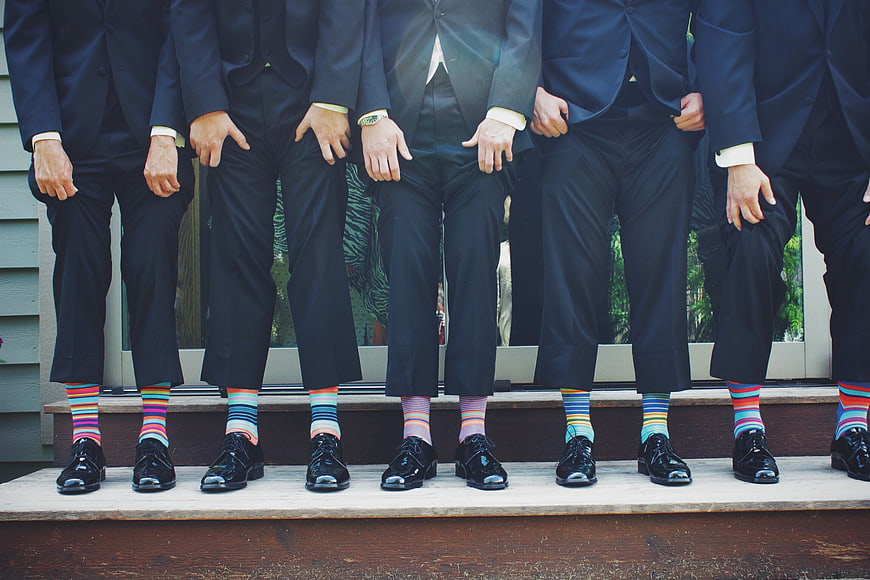 Men in suits wearing colorful striped socks on steps