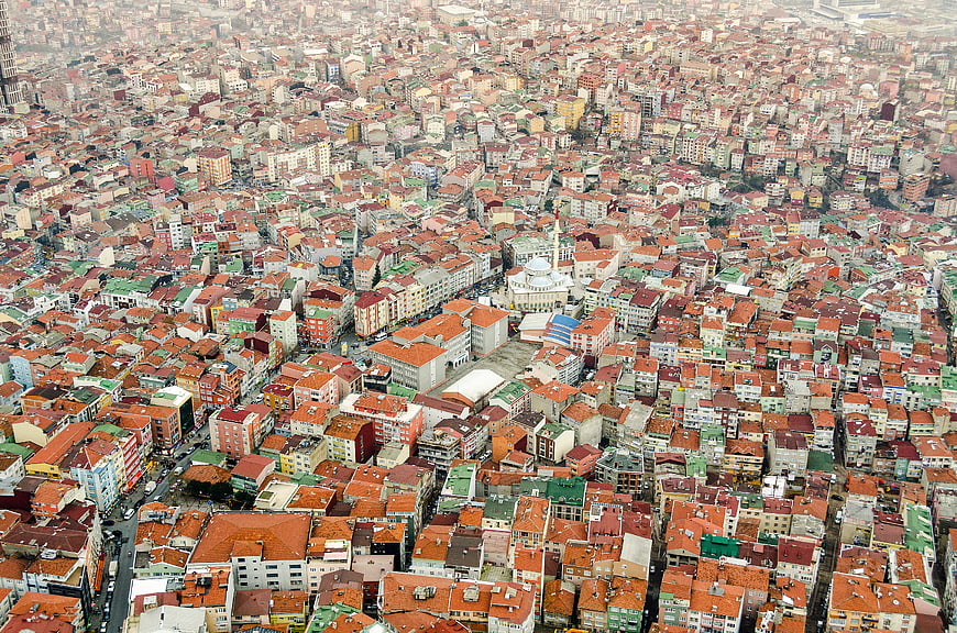 Aerial view of dense cityscape with red roofs and mosque