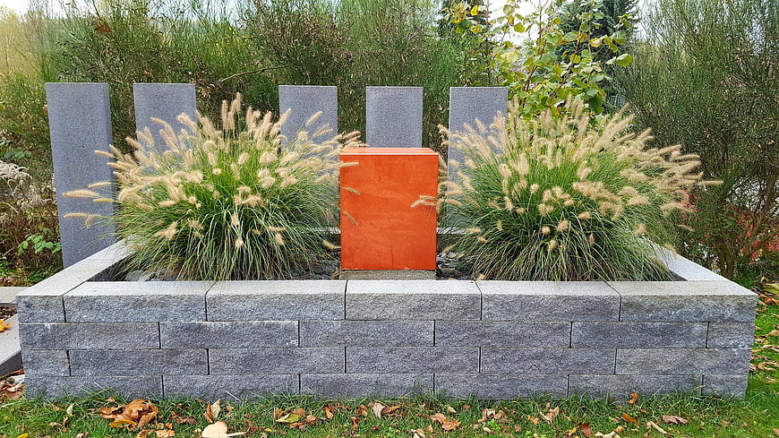 Modern garden planter with ornamental grasses and orange cube