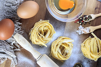 Fresh Pasta Nests with Eggs and Ingredients on Wooden Table