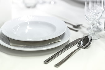Elegant white table setting with silver cutlery and glass