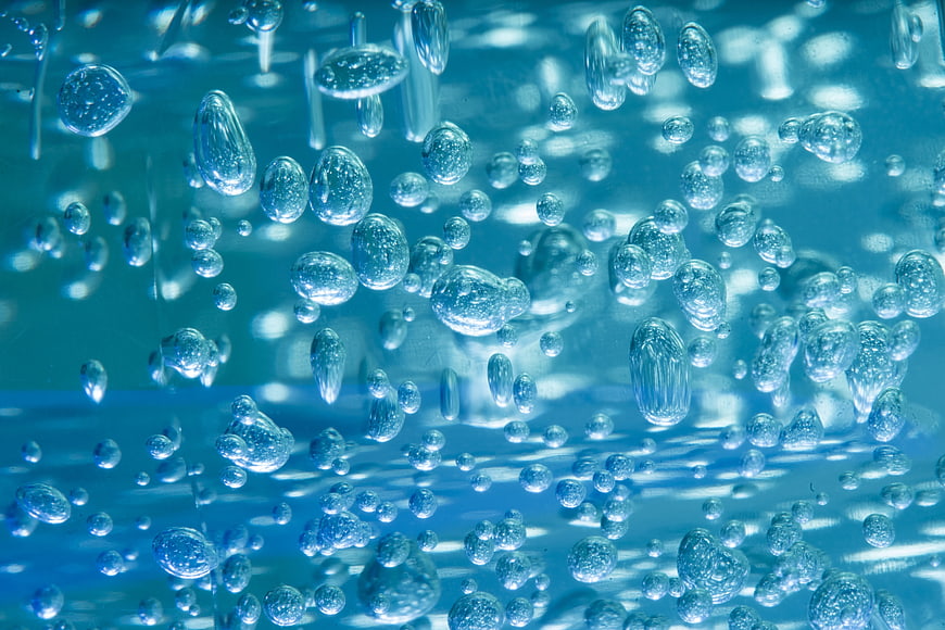 Close-up of rising water bubbles in blue liquid