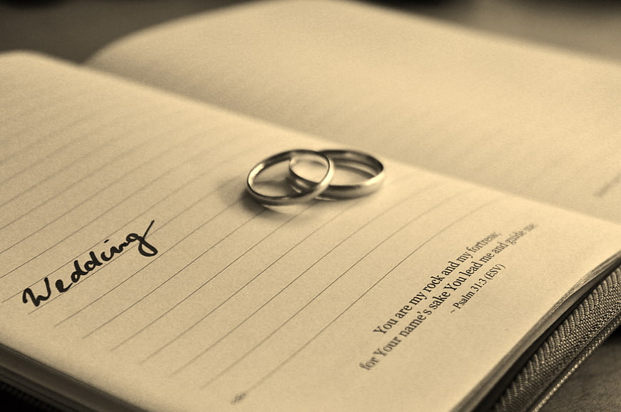 Wedding rings on open notebook with handwritten wedding text and Psalm 31:3
