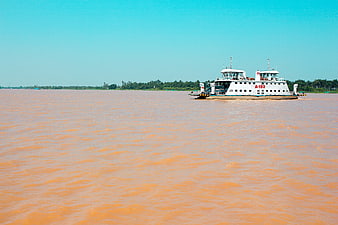 White ferry boat navigating a wide muddy river