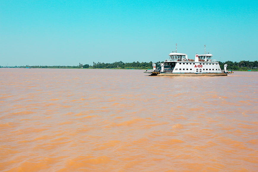 White ferry boat navigating a wide muddy river