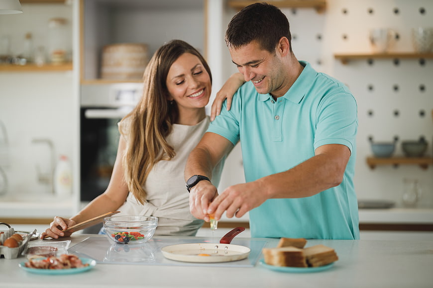 Happy couple cooking breakfast together in modern kitchen