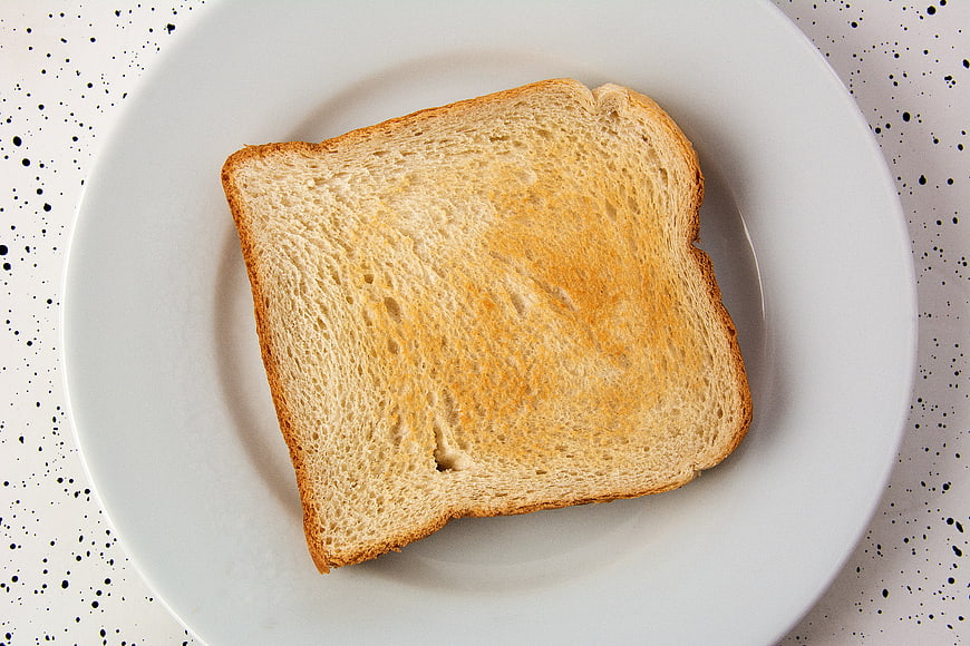Single slice of toasted white bread on a white plate