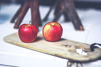 Two red apples on rustic wooden board