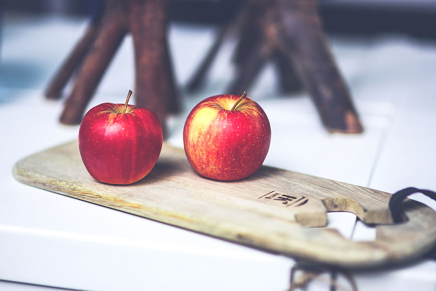 Two red apples on rustic wooden board