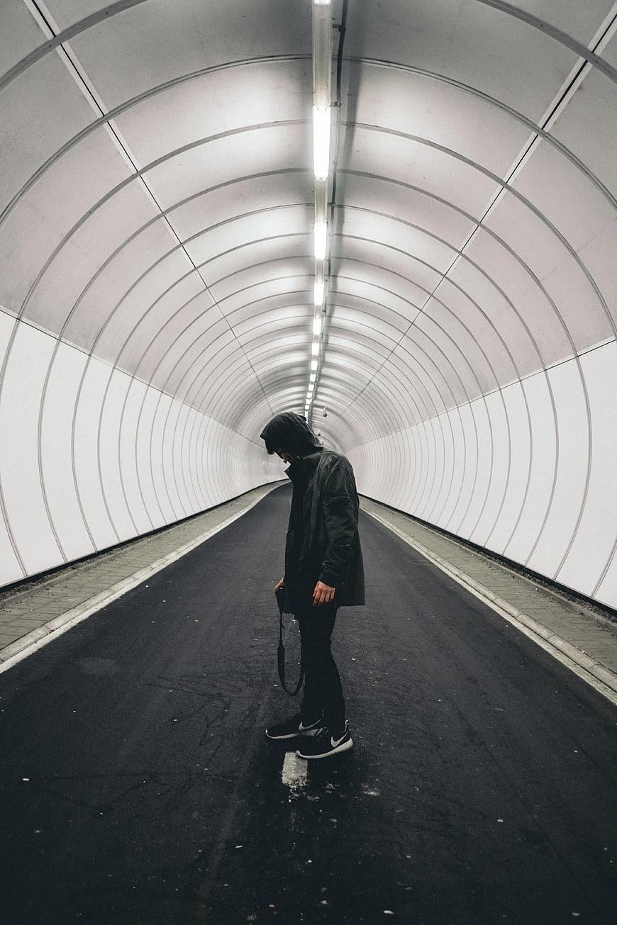 Man in Black Hoodie Standing in White Tunnel