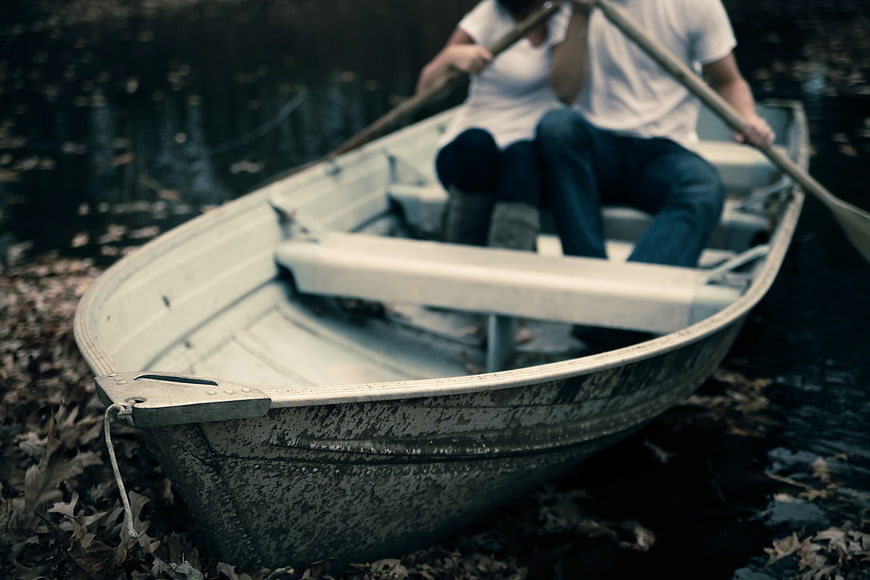 Couple rowing a boat on a lake with fallen leaves