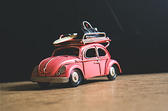 Vintage Red Toy Beetle Car with Surfboard on Roof Rack