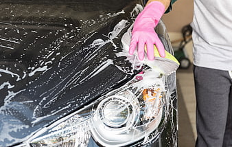 Person washing black car with pink gloves and sponge
