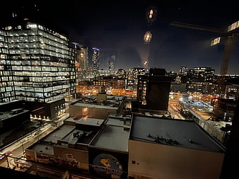 Nighttime city skyline view from rooftop with construction crane