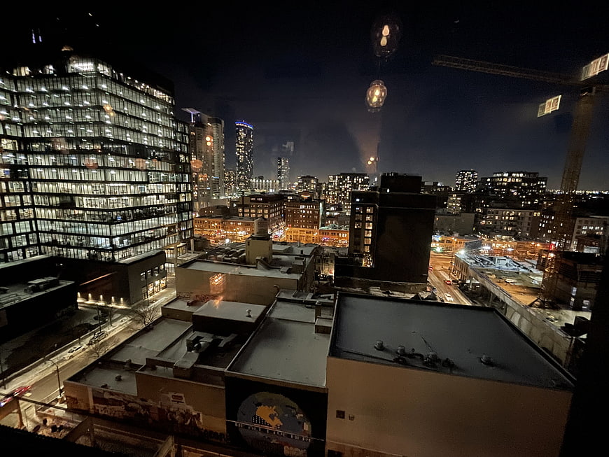 Nighttime city skyline view from rooftop with construction crane