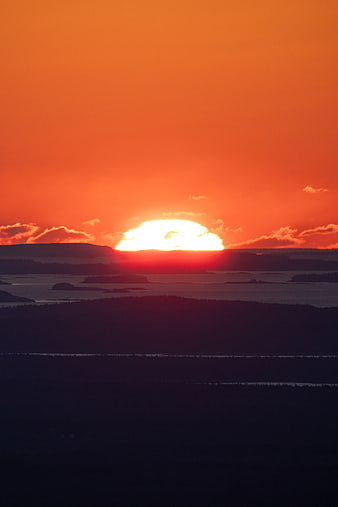 Vibrant Orange Sunset Over Silhouetted Coastal Landscape