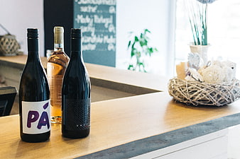 Wine bottles on a wooden bar counter with chalkboard background