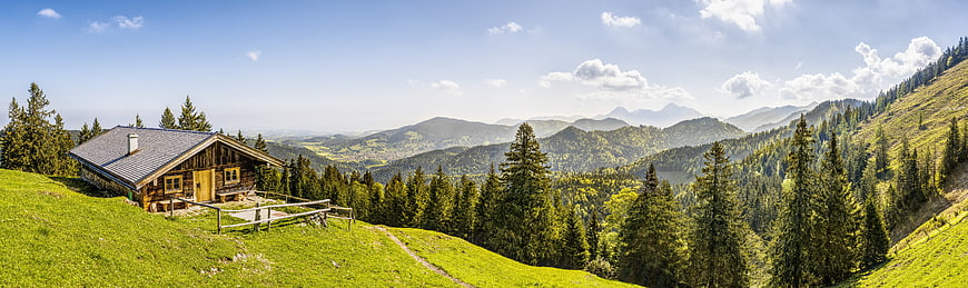 Panoramic view of wooden alpine cabin on green mountain slope