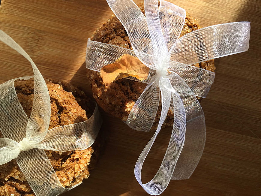 Homemade sugar cookies tied with white ribbon on wood