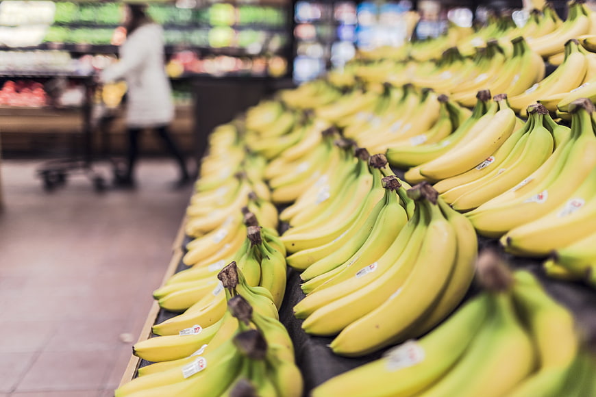 Rows of fresh yellow bananas in a grocery store produce section