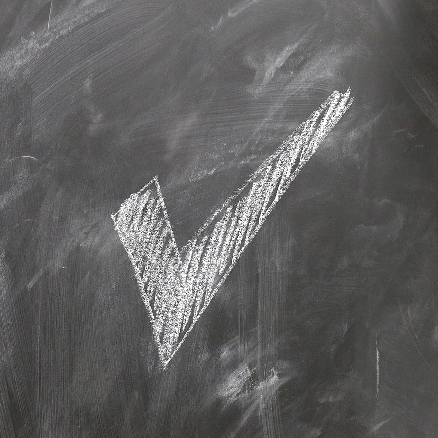 White Chalk Checkmark On Textured Blackboard Surface