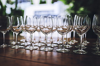 Rows of empty wine glasses on a wooden table