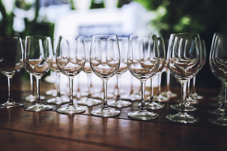 Rows of empty wine glasses on a wooden table