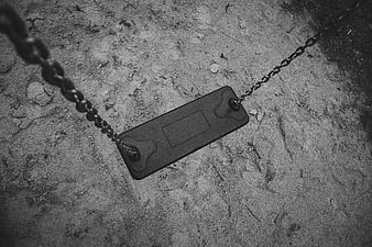 Empty black and white swing set in sandy playground