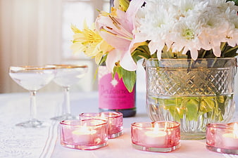 Romantic table setting with pink candles, flowers, and champagne glasses