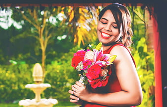 Happy woman holding colorful bouquet in garden