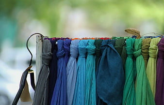 Colorful knotted scarves hanging on a wooden display rack