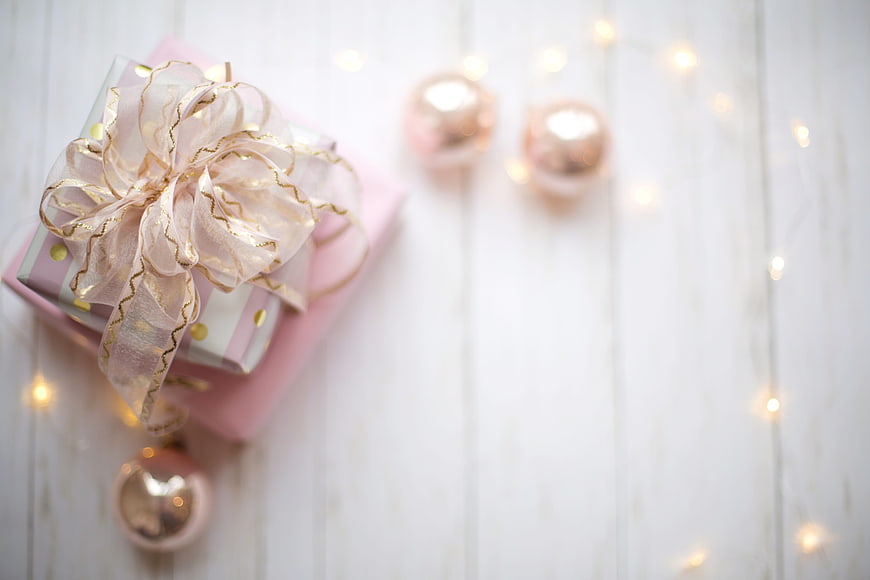 Pink Christmas Gift Box With Ribbon And Ornaments On White Wood